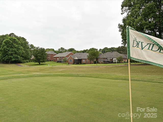 view of property's community featuring a lawn, a residential view, and view of golf course