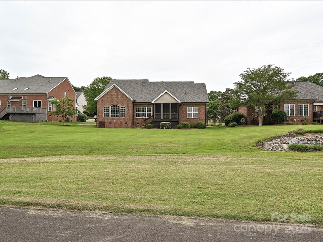 view of front facade featuring brick siding, a front yard, and a sunroom