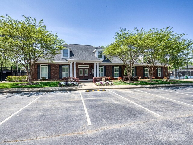 view of front of property featuring fence, uncovered parking, and french doors