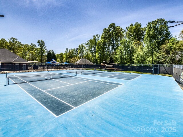 view of tennis court featuring fence and view of scattered trees