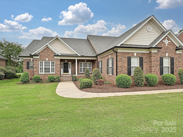 traditional home with brick siding, a front yard, a shingled roof, and a porch