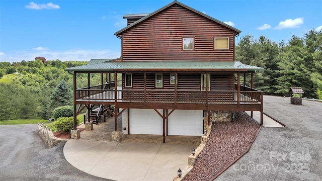 199 Joriann Dr, Crumpler, NC 28617 - view of home's exterior featuring an attached garage, metal roof, log veneer siding, and driveway