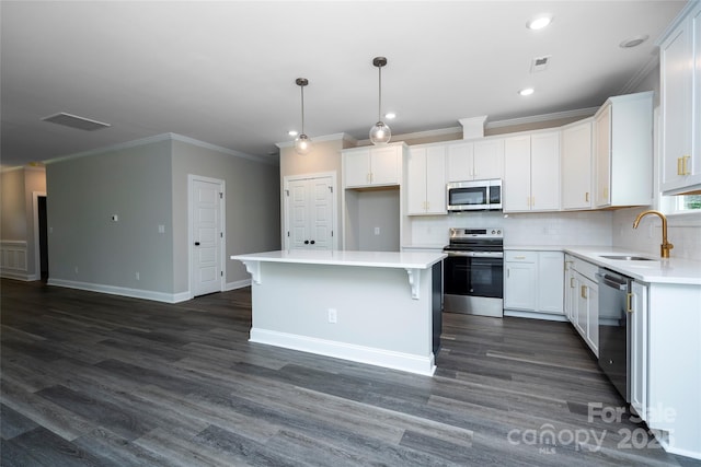kitchen with dark wood-style flooring, a sink, crown molding, a kitchen island, and appliances with stainless steel finishes
