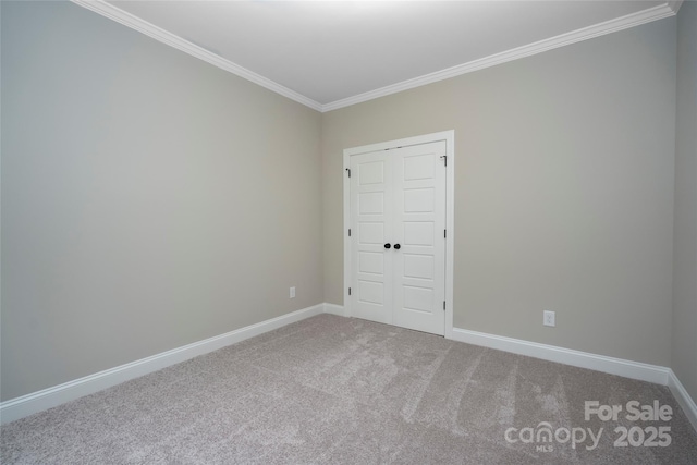 spare room featuring baseboards, carpet, and crown molding