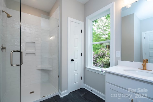 full bath featuring a stall shower, baseboards, vanity, and plenty of natural light