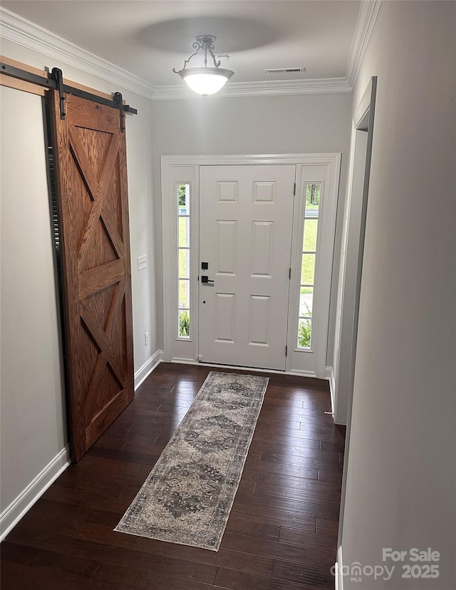 entrance foyer featuring crown molding, visible vents, a barn door, and dark wood finished floors