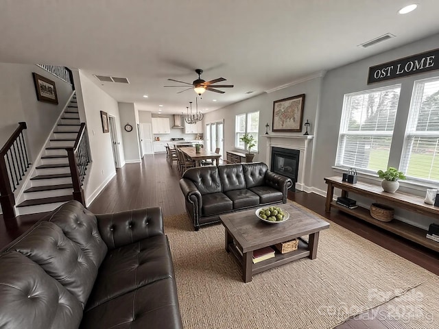living area featuring dark wood finished floors, stairway, visible vents, and ceiling fan