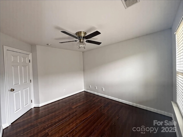 empty room featuring dark wood-type flooring, visible vents, baseboards, and a ceiling fan