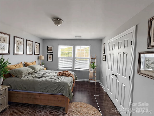 bedroom with a closet, visible vents, baseboards, and dark wood finished floors