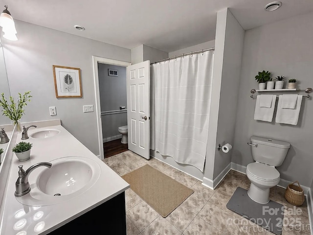 bathroom with toilet, double vanity, a sink, and visible vents