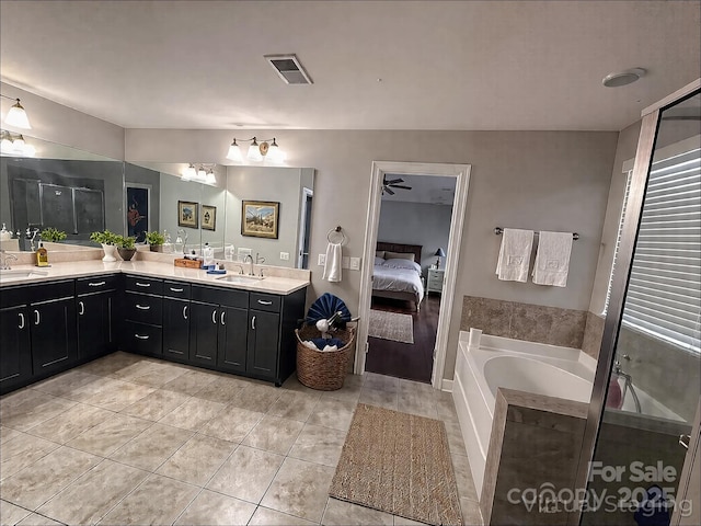 ensuite bathroom with double vanity, a garden tub, and a sink