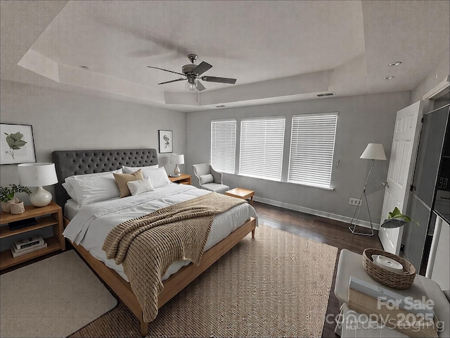 bedroom featuring visible vents, a tray ceiling, and baseboards