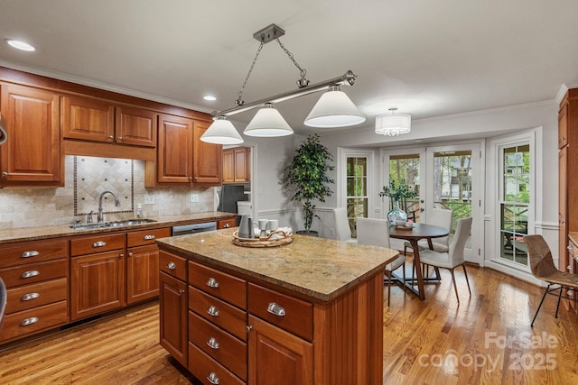 5125 Winding Brook Rd, Charlotte, NC 28226 - kitchen featuring a center island, brown cabinets, light wood-type flooring, and a sink