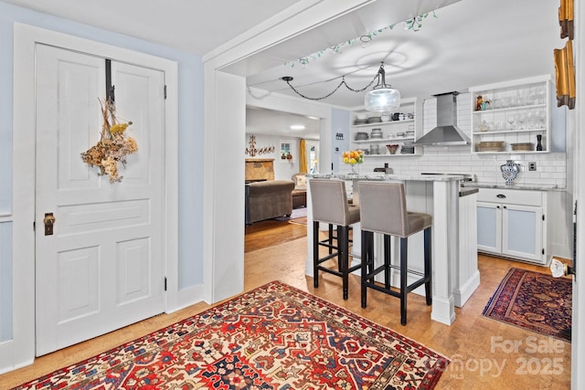 144 Miller Dr, Tryon, NC 28782 - kitchen with wall chimney exhaust hood, a kitchen bar, tasteful backsplash, white cabinetry, and open shelves