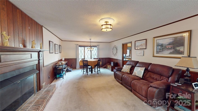 living area featuring light carpet, a fireplace, a textured ceiling, a wainscoted wall, and wood walls