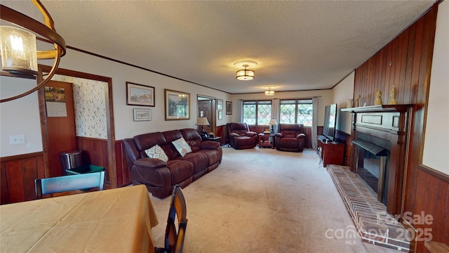 carpeted living area featuring crown molding, a textured ceiling, wood walls, wainscoting, and a brick fireplace
