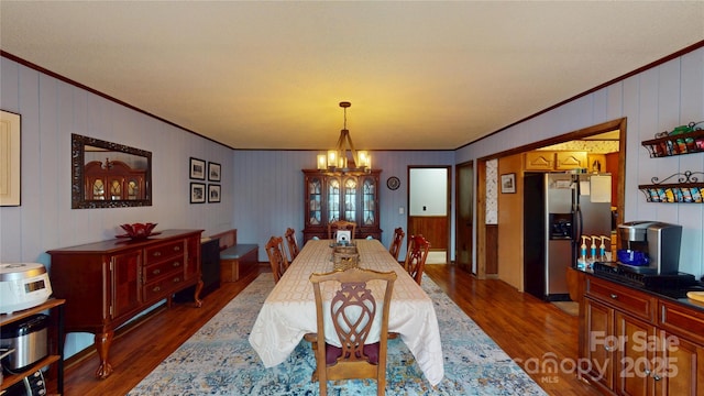 dining space featuring crown molding, an inviting chandelier, and dark wood-style floors