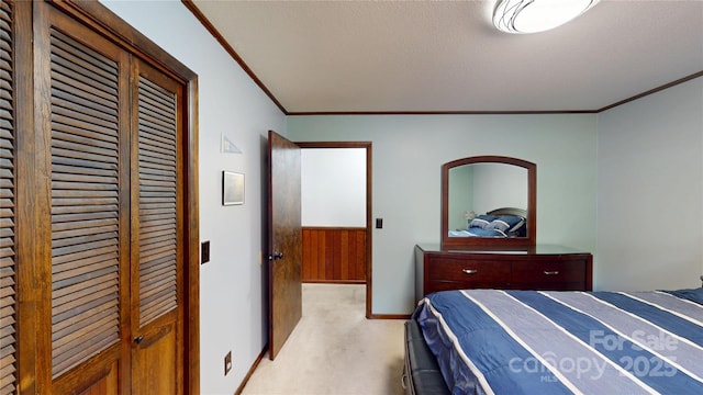 bedroom featuring a closet, baseboards, ornamental molding, a textured ceiling, and light colored carpet