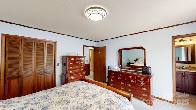 bedroom with a closet, baseboards, ornamental molding, ensuite bath, and light colored carpet