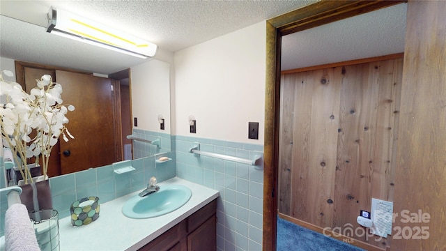 bathroom with a textured ceiling, vanity, and wainscoting