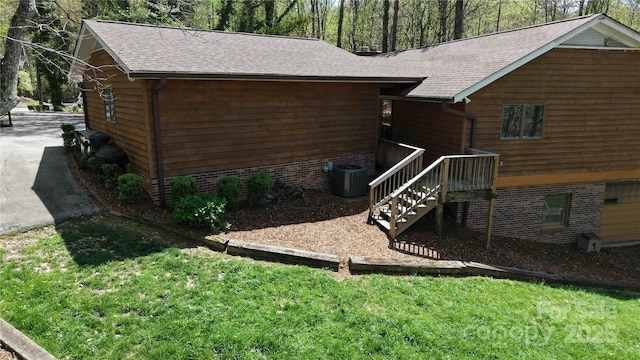 view of home's exterior with a yard, roof with shingles, and central AC