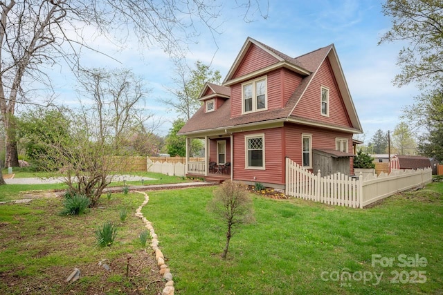 view of front of home featuring a front lawn, fence, and a shingled roof