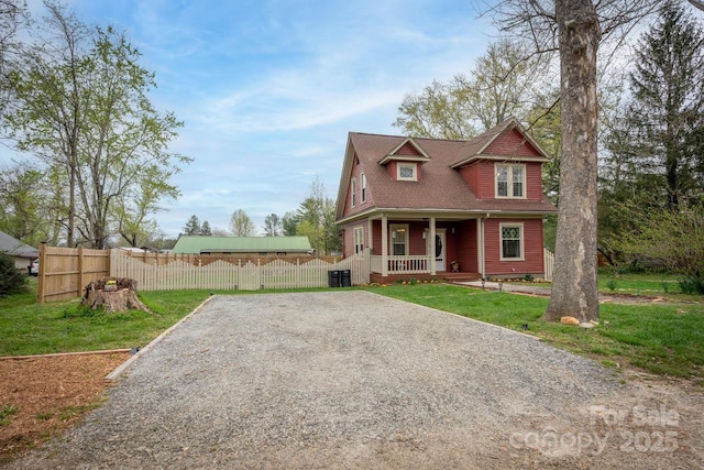 victorian home featuring gravel driveway, covered porch, a front yard, and fence