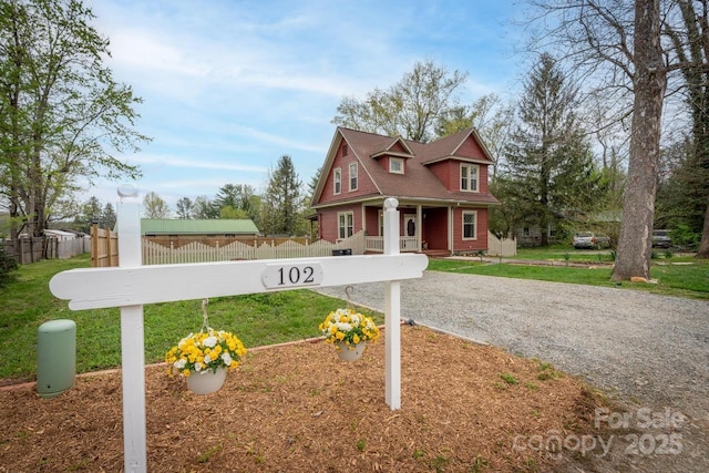 exterior space featuring gravel driveway, fence, and a lawn