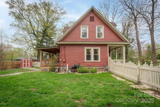 back of property with an outbuilding, a fenced backyard, a yard, and a shed