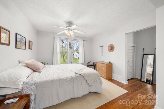 bedroom with a ceiling fan, wood finished floors, and a textured ceiling