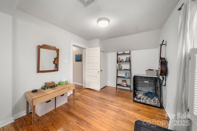 interior space with a textured ceiling, baseboards, visible vents, and light wood-style floors