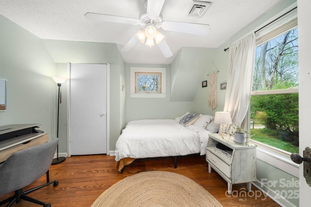 bedroom featuring visible vents, multiple windows, a textured ceiling, and a ceiling fan