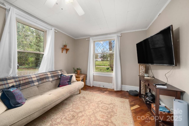 living room with ornamental molding, ceiling fan, wood finished floors, and baseboards
