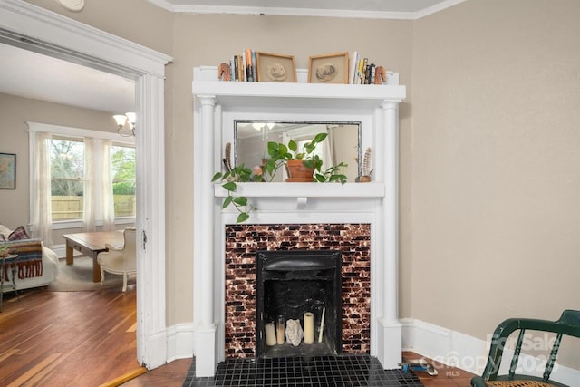 interior details with crown molding, an inviting chandelier, wood finished floors, and a fireplace
