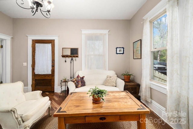 living area featuring an inviting chandelier, baseboards, dark wood-style floors, and a wealth of natural light