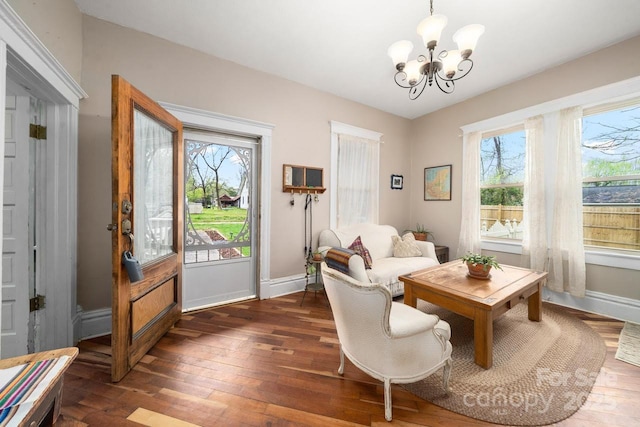 sitting room featuring dark wood-type flooring, an inviting chandelier, and baseboards