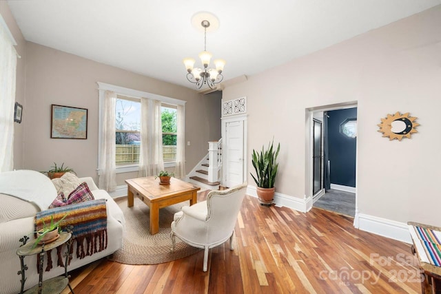 living room with light wood-style flooring, stairway, a notable chandelier, and baseboards