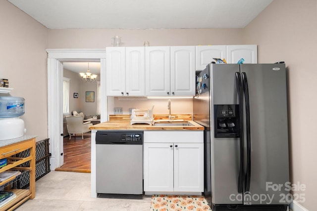 kitchen featuring a sink, white cabinetry, an inviting chandelier, and stainless steel appliances