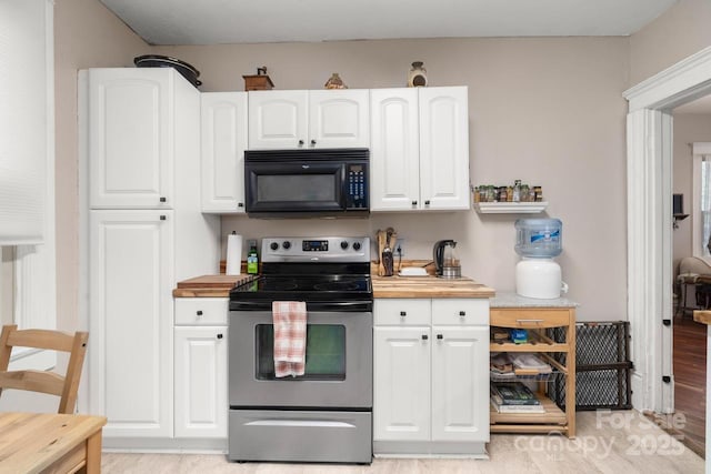 kitchen featuring electric stove, black microwave, white cabinets, and butcher block countertops