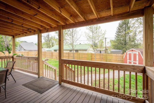 deck with a fenced backyard, an outdoor structure, a lawn, and a storage unit