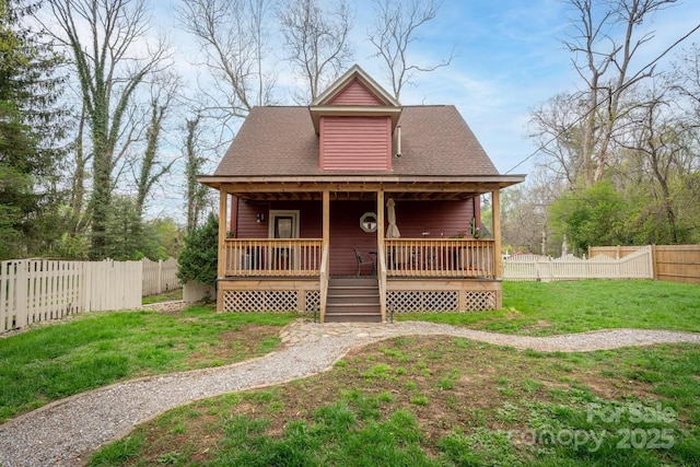 view of front of house with a fenced backyard, a front lawn, a shingled roof, and covered porch