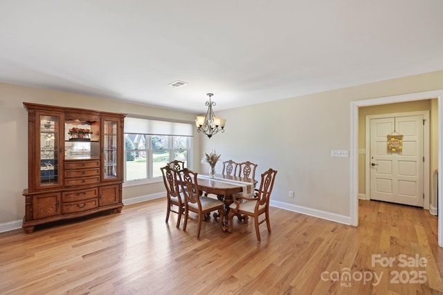 dining area featuring baseboards, visible vents, a chandelier, and light wood finished floors