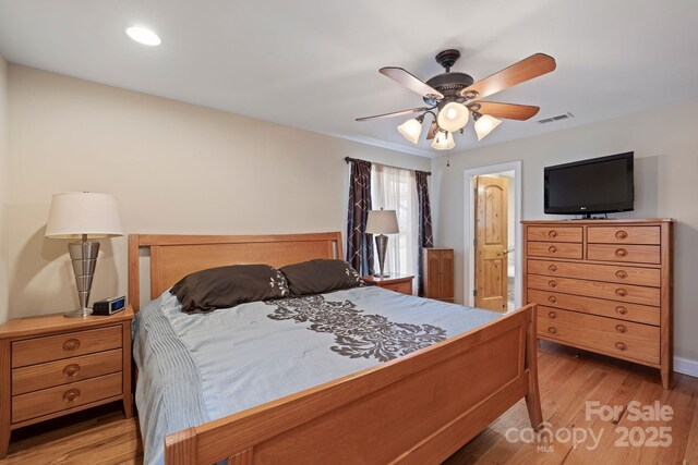 bedroom featuring connected bathroom, visible vents, light wood-style flooring, and a ceiling fan
