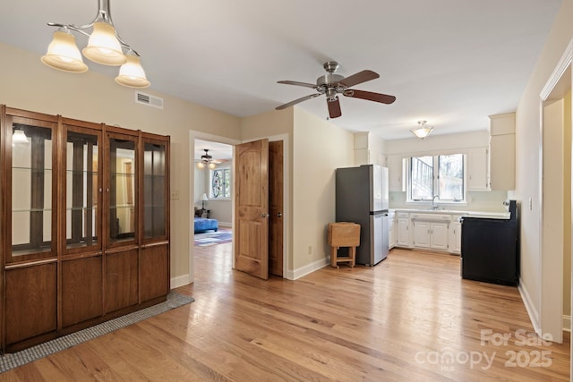 interior space featuring light countertops, visible vents, light wood-style flooring, ceiling fan, and freestanding refrigerator
