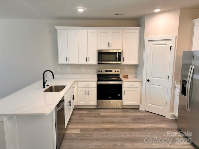 1218 Fall Day Cir SW, Lenoir, NC 28645 - kitchen featuring stainless steel appliances, a peninsula, recessed lighting, wood finished floors, and white cabinetry