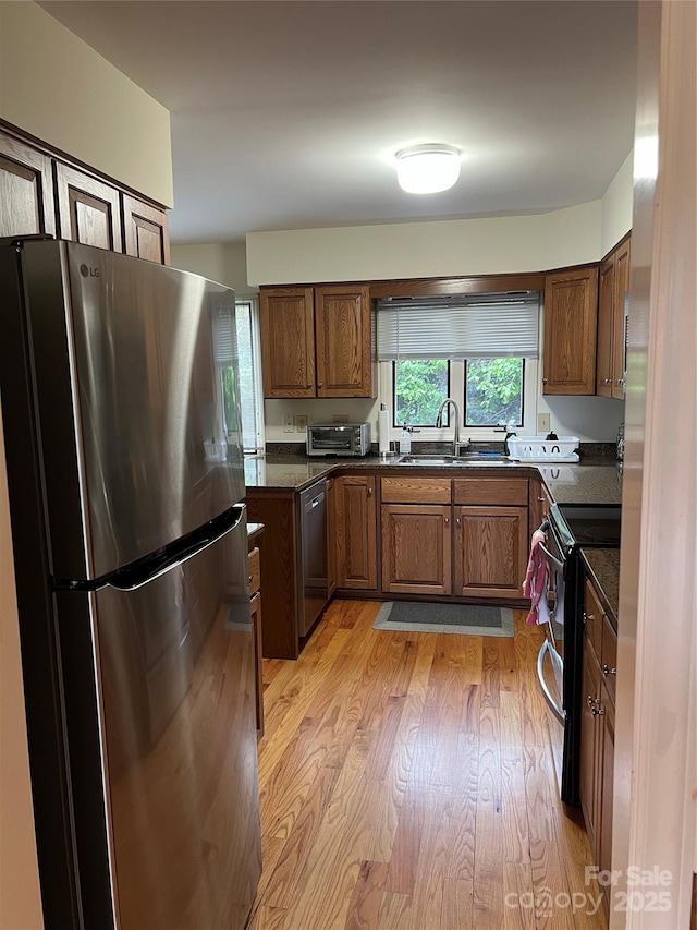 kitchen with a sink, freestanding refrigerator, electric range oven, and dark countertops