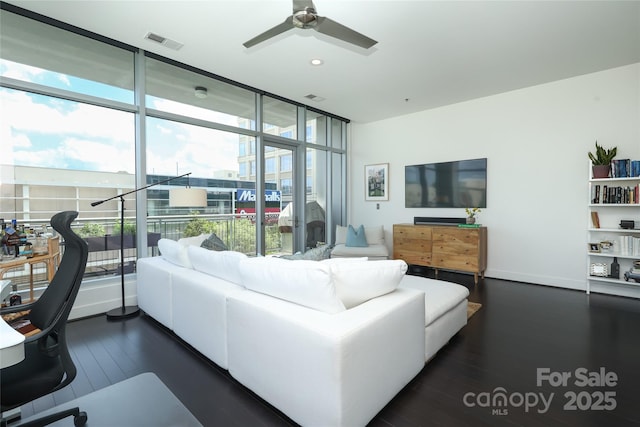 living room with a wealth of natural light, visible vents, dark wood-style floors, and ceiling fan