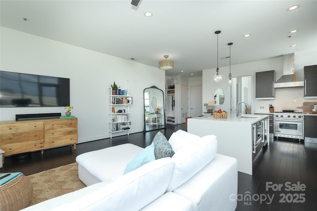 living area with dark wood-style flooring, baseboards, and recessed lighting