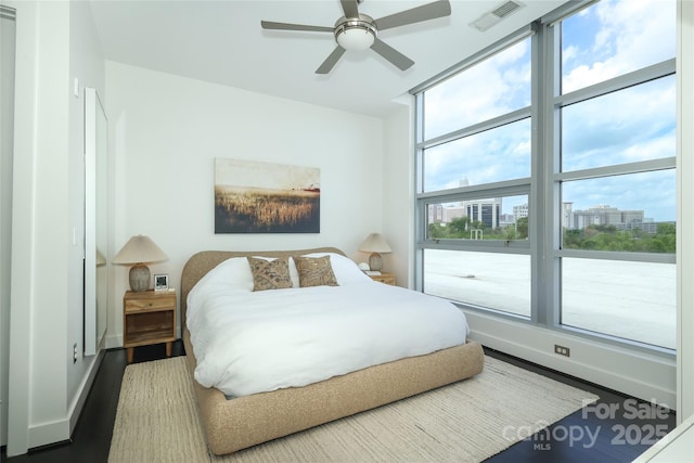 bedroom featuring visible vents, baseboards, wood finished floors, and a city view