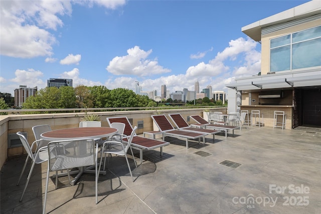 view of patio / terrace featuring a view of city, outdoor dining area, outdoor dry bar, and area for grilling